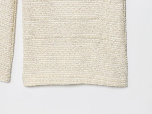 Détail du tissu en tweed crème et des coutures sur l'ensemble gilet et pantalon en maille