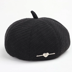 Detail of black knit beret showing textured twill fabric and silver heart metal buckle