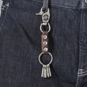 Vintage brown leather keychain with skull embossed metal clip on blue denim jeans