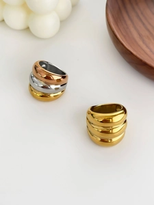 Close-up of triple-layered stacked rings in mixed gold and silver finishes on white surface