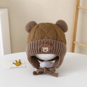 Detail of brown quilted trapper hat for kids featuring cute bear embroidery and 3D ears