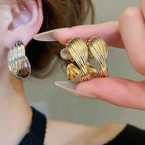 Close-up of twisted round hoop earrings in gold and silver finish with spiral texture