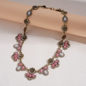 Close-up of vintage gold necklace with pink resin stones and crystal floral details