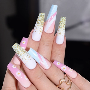 Detail of long coffin press-on nails with pink ombre, white daisies, and gold glitter accents