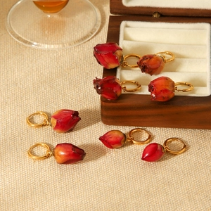 Elegant gold hoop earrings with natural red rose flower buds on beige fabric