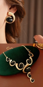 Detail of vintage gold jewelry set with oval black stones on green velvet and model view