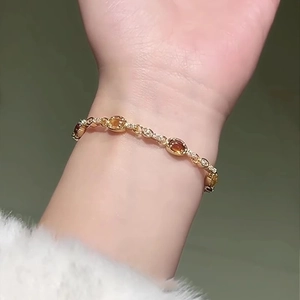 Close-up of 18k gold-plated oval amber resin bracelet with sparkling crystal accents