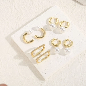 Flat lay of diverse bohemian pearl and zircon gold earrings on minimalist stone texture