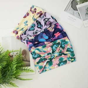 Flat lay of four wide elastic yoga headbands with vibrant butterfly and floral prints