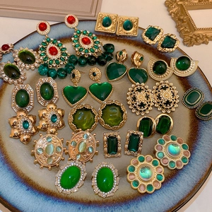 Detailed view of vintage green heart and floral earrings displayed on a ceramic tray