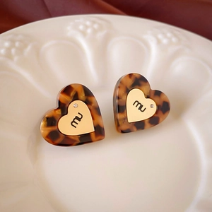 Detail of tortoiseshell resin heart earring with golden metal inlay on ceramic plate