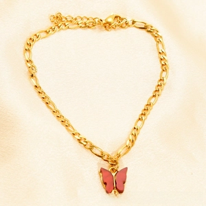 Detail of 18K gold Figaro chain anklet featuring a translucent red butterfly charm
