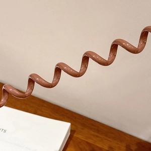 Détail de l'élastique à cheveux spirale marron avec une finition brillante et souple