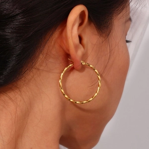 Detail of twisted 18K gold plated thick hoop earrings on a model showing texture and size