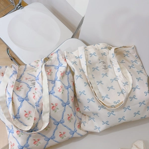 Floral canvas tote bags with blue ribbon patterns and roses on a white chair