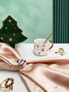 Close-up of festive Christmas table setting with snowman mug and themed napkin rings