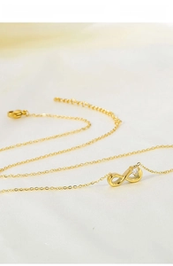 Macro shot of gold infinity pendant with zircon detail on titanium steel chain