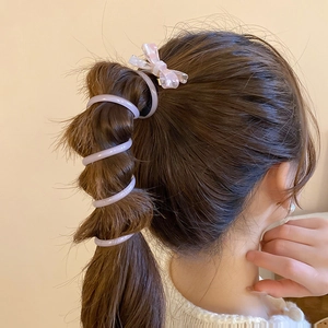 Détail de l'élastique spirale violet et pince à nœud rose à carreaux avec perles