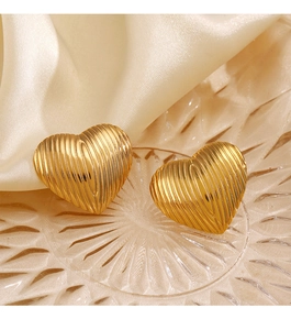 Detail view of golden heart stud earrings with vertical wavy texture on relief glass