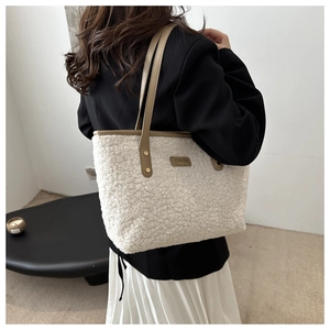 Close-up of white sherpa tote bag with khaki leather trim and metallic rivet details