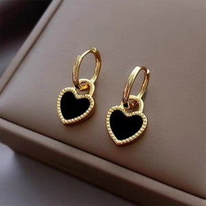 Macro shot of elegant black and gold heart pendant hoop earrings with beaded edge detail
