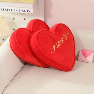 Plush heart pillows in red with gold I Love You embroidery on a cozy living room sofa