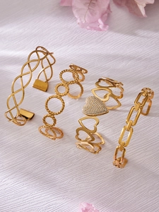 Detailed macro view of four assorted gold plated stainless steel bangles with floral accents