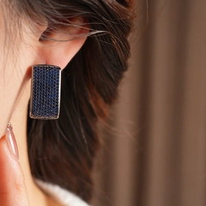 Macro shot of rectangular blue zircon earrings worn by a model in a luxury vintage style