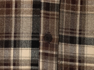 Macro shot of brown plaid fabric with twill texture and a dark brown button detail