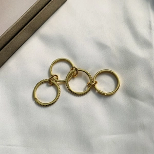 Detailed view of four interlocking gold rings with pavé crystals on white silk