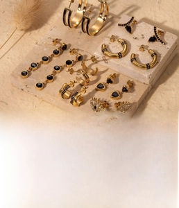 Gros plan détaillé de boucles d'oreilles dorées en acier titane avec œil et cœur sur pierre