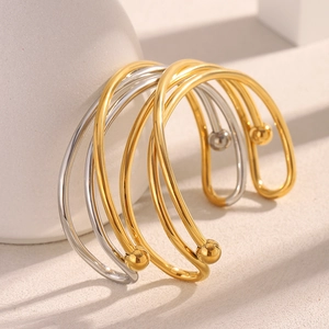Détail de joncs croisés minimalistes plaqués or 18 carats et argent avec perles