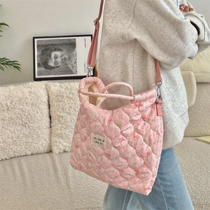 Detailed texture of pink quilted tote bag with cute rabbit and floral embroidery patterns