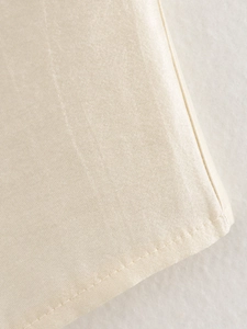 Detailaufnahme von cremefarbenem Satinstoff mit feinen Nähten und seidiger Textur