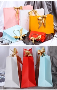 Detailed view of colorful paper gift bags with golden ribbon bows and braided handles
