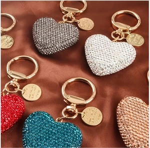 Close-up of heart-shaped rhinestone keychains in multiple colors on silk fabric