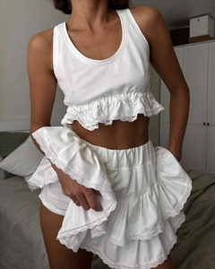 Detail of white lace ruffle mini skirt and sleeveless crop top two-piece set for women