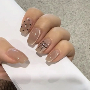 Pink cat eye press-on nails with black polka dots and elegant bow pearl accents
