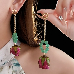 Details langer Perlenohrringe mit Goldmetall und konservierten rosa Rosenknospen
