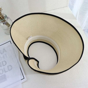 Close-up of beige straw visor hat featuring black edge trim and soft inner sweatband detail
