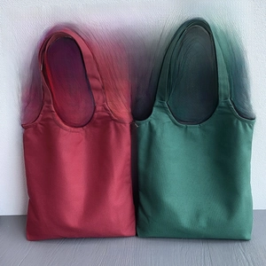 Detail view of burgundy and dark green canvas tote bags showing thick fabric texture