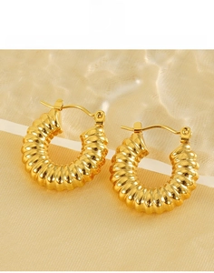 Close-up of golden spiral texture on 18k titanium steel hoop earrings with silk background