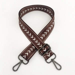 Detail of dark brown nylon strap with white arrow pattern and dark grey metal buckle