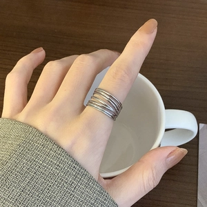 Close-up of minimalist multi-layer silver winding ring worn on index finger with a mug
