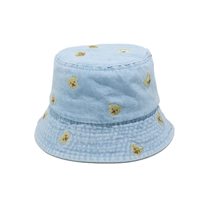 Detail showing teddy bear embroidery on light blue denim bucket hat fabric and stitching