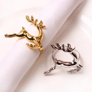 Close-up of gold and silver reindeer napkin rings on white linen for festive table decor