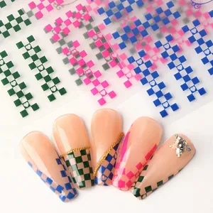 Detail view of colorful checkerboard nail art stickers with heart patterns on long nails