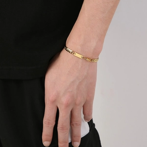 Detail of a polished gold-plated flat chain bracelet with a rectangular nameplate on wrist