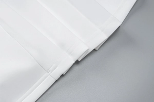Macro shot of white fabric texture and fine stitching detail on a short ruffled dress