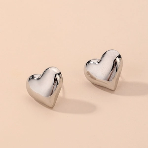 Détail macro de boucles d'oreilles cœur en argent poli avec un design minimaliste 3D